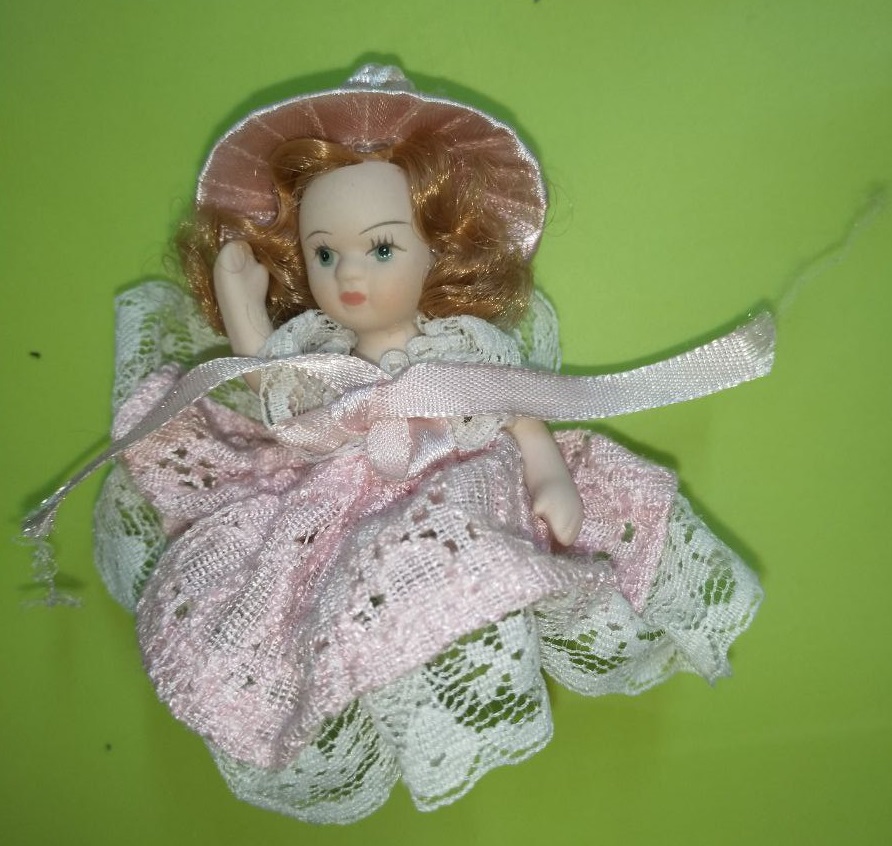 Small porcelain doll (6 cm) sitting on heart swing